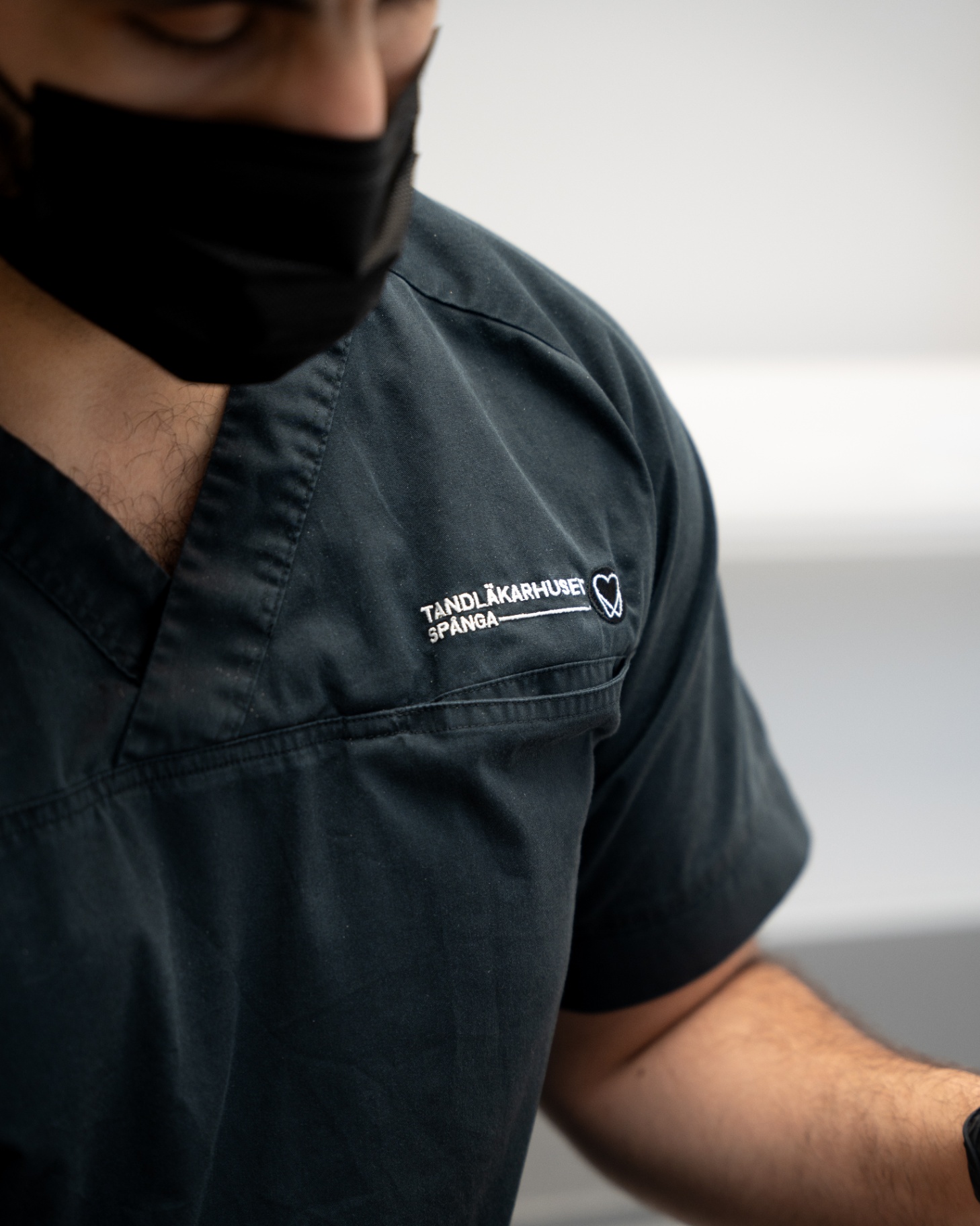 Närbild på personalens scrubs med Tandläkarhuset Spångas logotyp